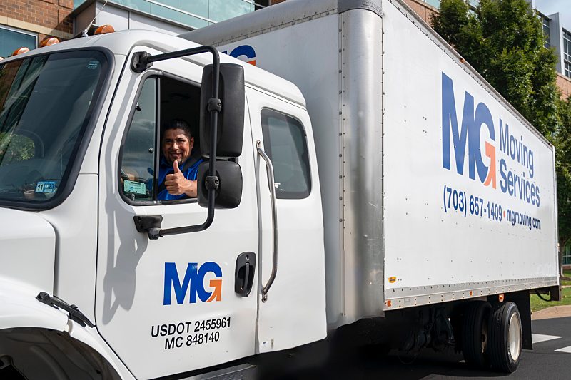 MG mover in an MG moving truck smiling during a last minute move