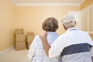 senior couple in room looking at moving boxes on floor