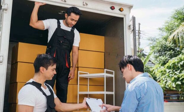 couple pleased signs the delivery checklist after professional movers help with furniture lifting