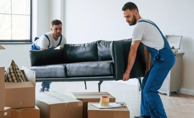 two moving service employees moving sofa in a room