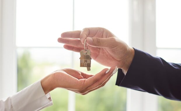 unrecognizable man estate agent gives key to woman client who buys house or apartment