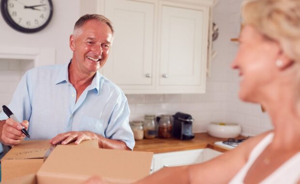 senior couple downsizing in retirement packing and labelling boxes ready for move into new home